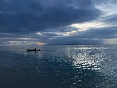 A canoe on calm water beneath a cloudy evening sky.