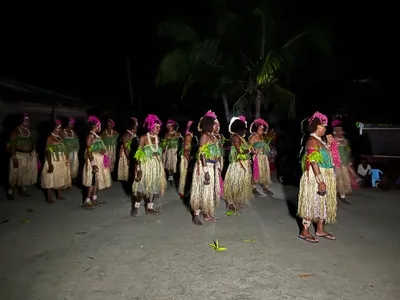 A group wearing leaf decorations gathers after dark.