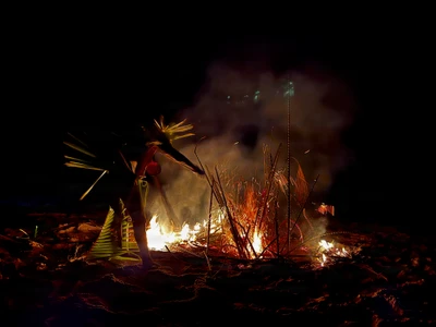 Participants with leaf decorations beside a nighttime bonfire.