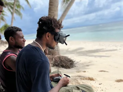 A man looks at a camera beside the beach.