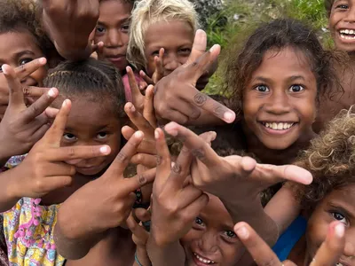Children smile and reach toward the camera.