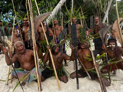 A group with leaf decorations holds poles and wooden paddles.