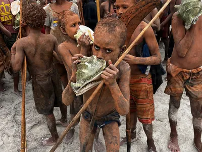 Children gather with wooden paddles and poles.
